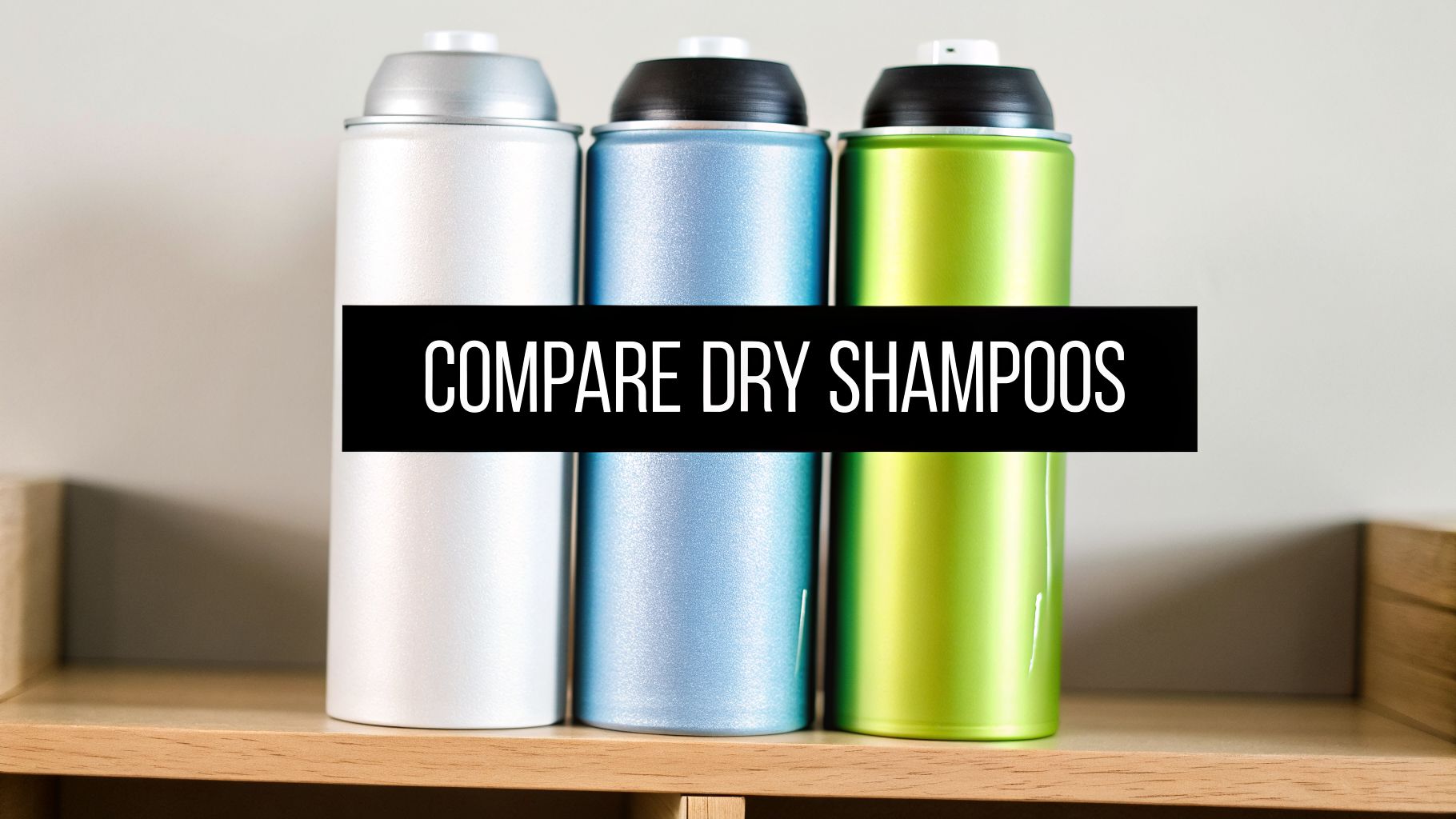 Three colorful aerosol cans of dry shampoo in silver, blue, and green on a wooden shelf, with a black banner that reads 'COMPARE DRY SHAMPOOS'.
