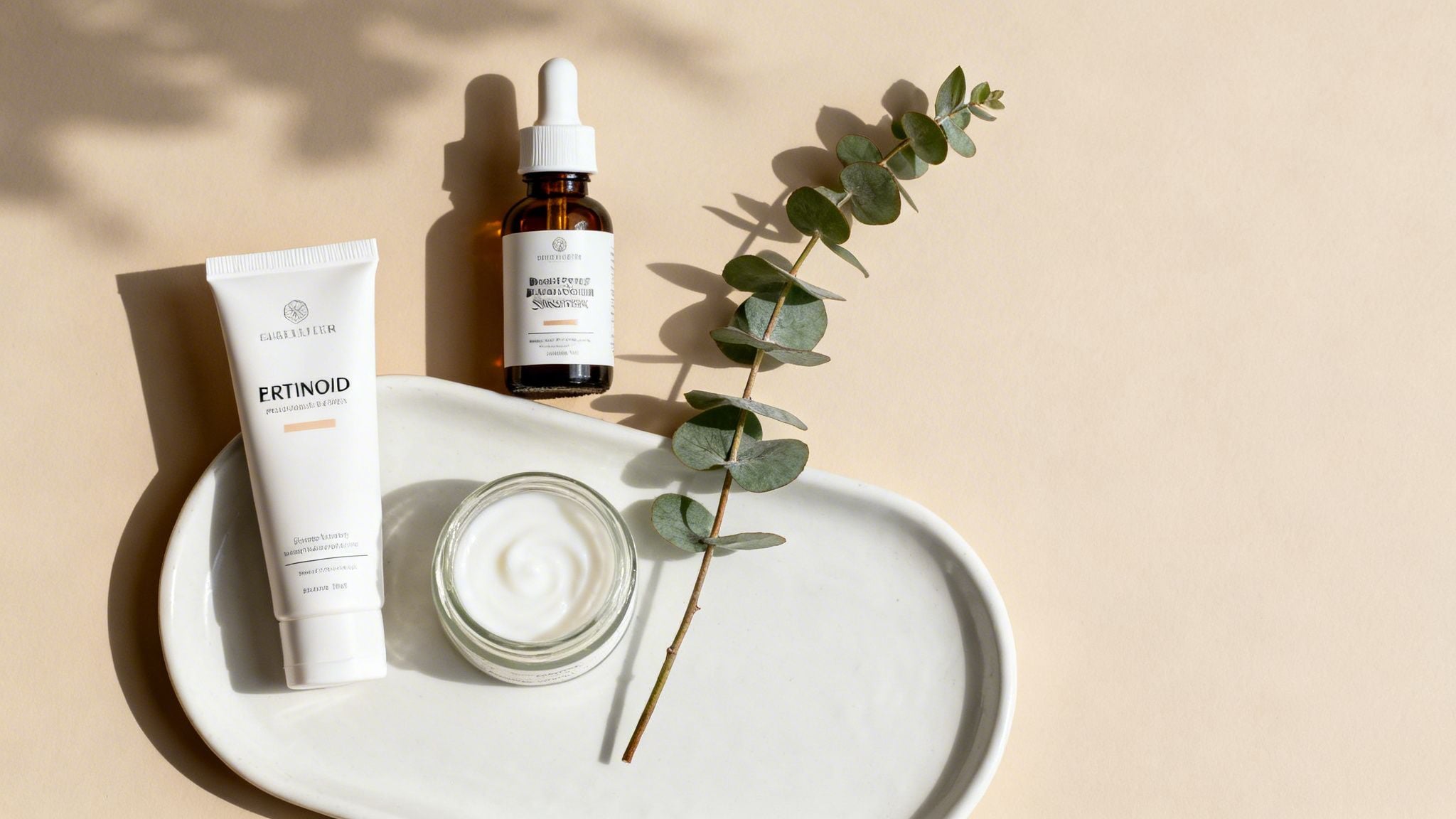 Flat lay of anti-aging skincare products, including a tube, serum, and cream, with eucalyptus.